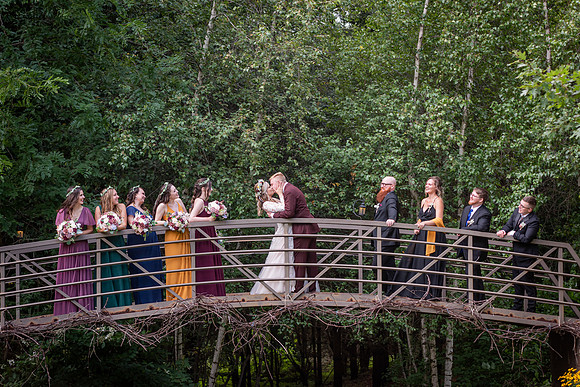 Bride and groom and their wedding party on a foot bridge by Cukini Studio